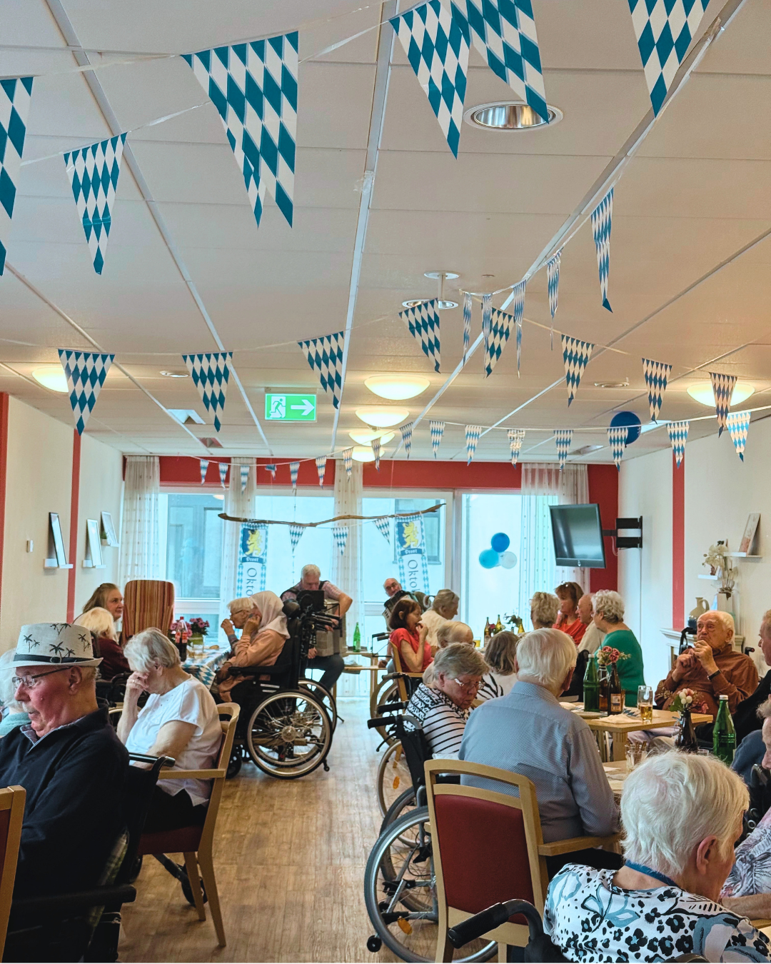 Seniorinnen und Senioren feiern gemeinsam Oktoberfest in einer neio-Tagespflege mit Brezeln und Musik